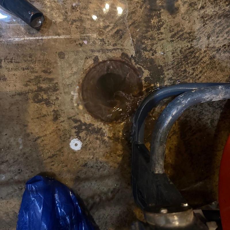 House trap drain cleaning with plumber hose in basement