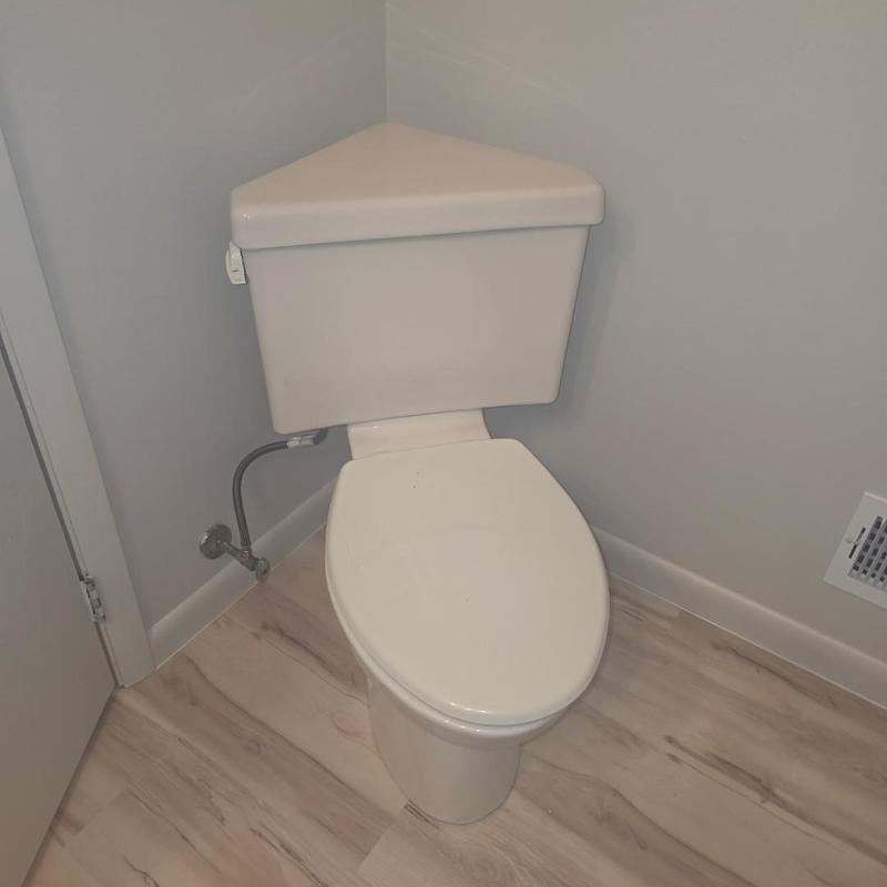 Corner toilet installation with angled tank and flooring
