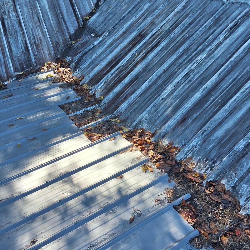 Metal roof panels with debris and damage near seam Metal roof panels with debris and damage near seam