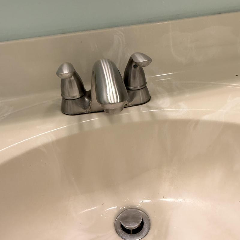 Lavatory faucet with dual handles on beige sink