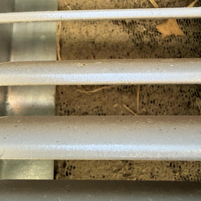 Metal air vent grille close-up over dirt floor
