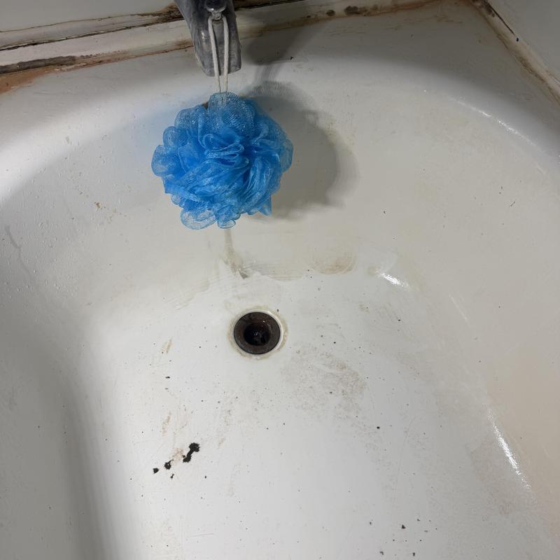 Bathtub drain with flowing water and blue scrubber Bathtub drain with flowing water and blue scrubber