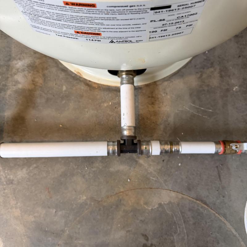 Pressure tank with connected white PVC piping and valve Pressure tank with connected white PVC piping and valve