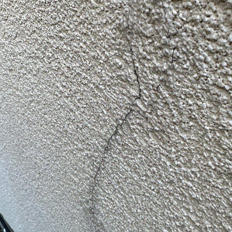 Stucco wall with textured surface and visible cracks Stucco wall with textured surface and visible cracks
