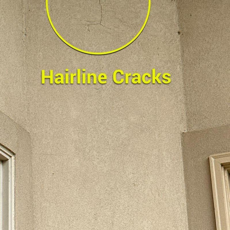 Stucco wall with hairline cracks near window frame Stucco wall with hairline cracks near window frame