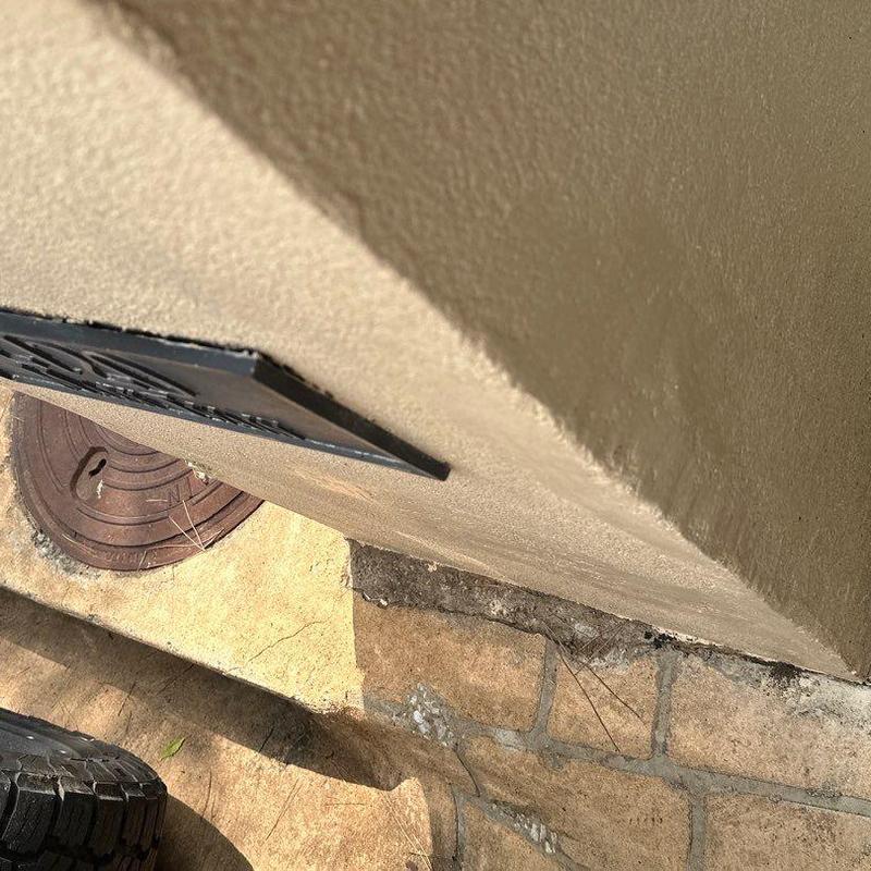 Stucco lower wall damage near metal vent and stone walkway Stucco lower wall damage near metal vent and stone walkway