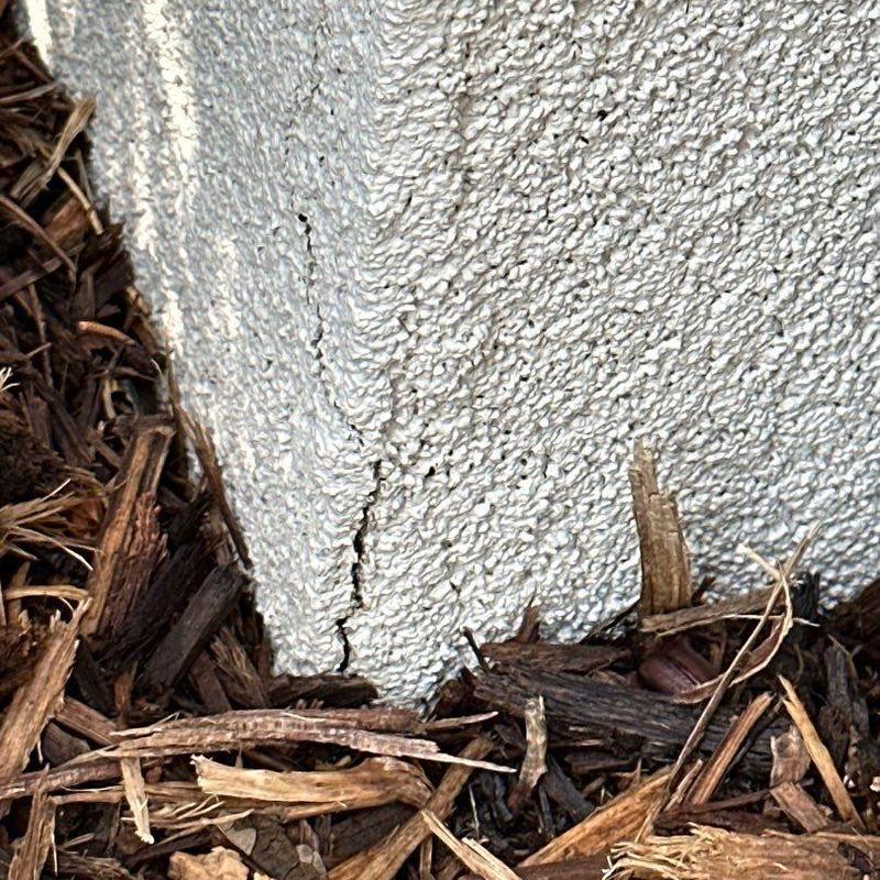 Stucco corner crack near ground with mulch base Stucco corner crack near ground with mulch base