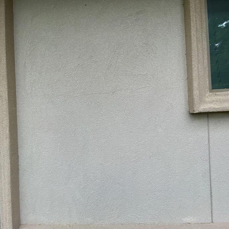 Stucco wall with hairline cracks near window frame Stucco wall with hairline cracks near window frame