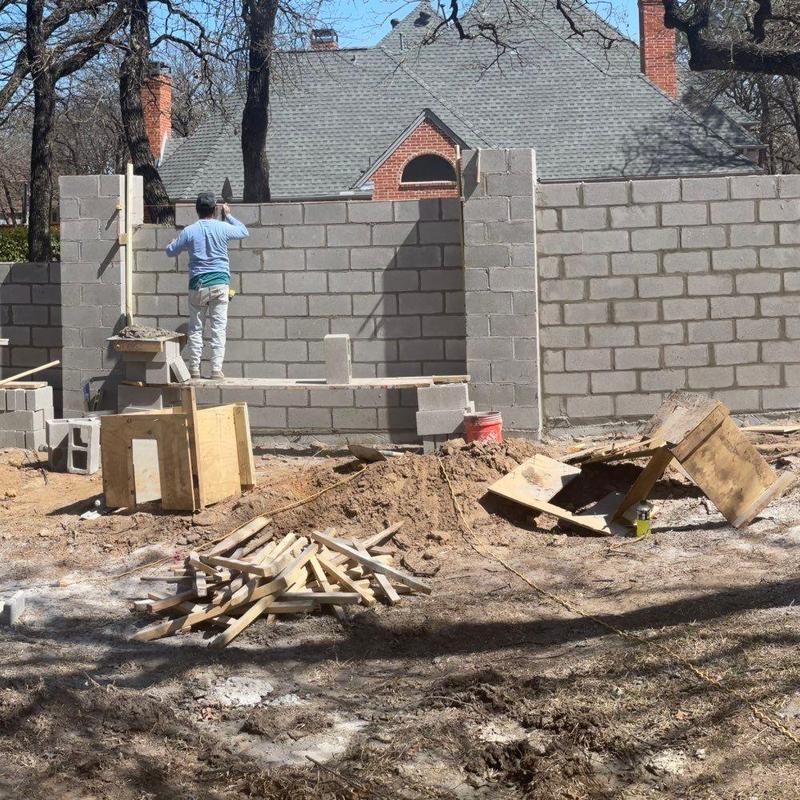 Concrete block wall construction with worker on scaffolding Concrete block wall construction with worker on scaffolding
