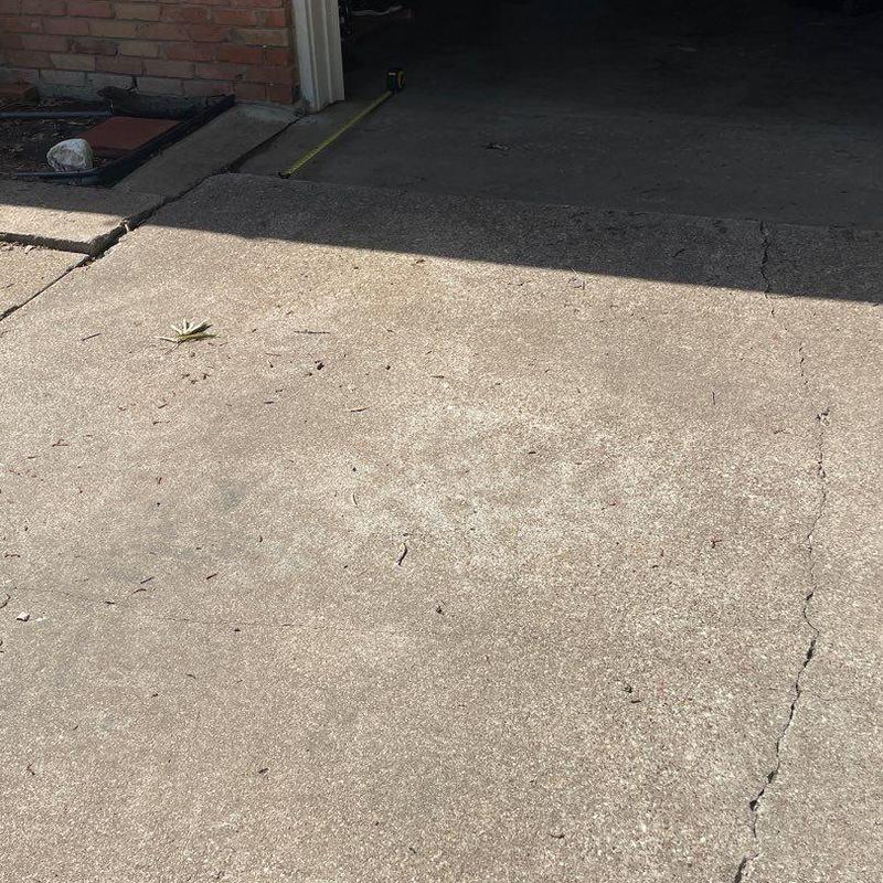 Concrete driveway with cracks near garage entrance Concrete driveway with cracks near garage entrance
