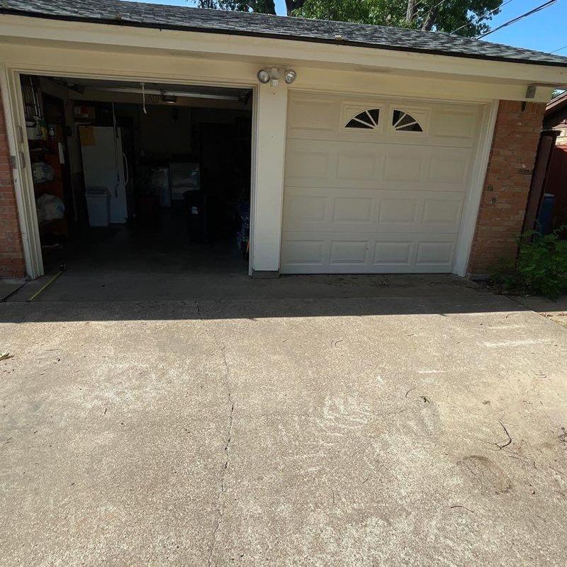 Concrete driveway cracks near garage entrance and lawn edge Concrete driveway cracks near garage entrance and lawn edge