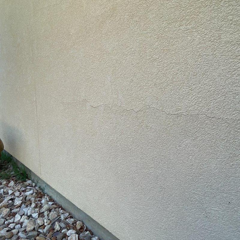 Stucco exterior crack above wall base and rocks Stucco exterior crack above wall base and rocks