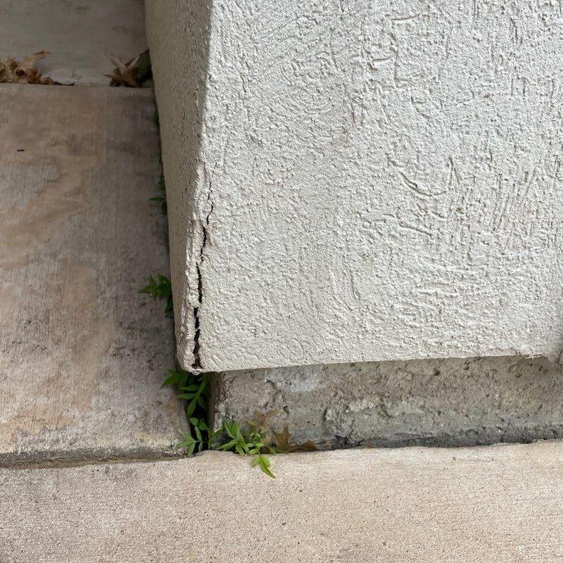 Stucco corner crack and concrete base with weeds Stucco corner crack and concrete base with weeds