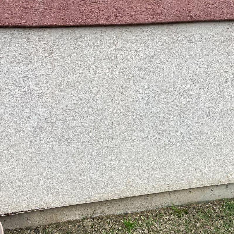 Stucco exterior wall with visible hairline crack Stucco exterior wall with visible hairline crack