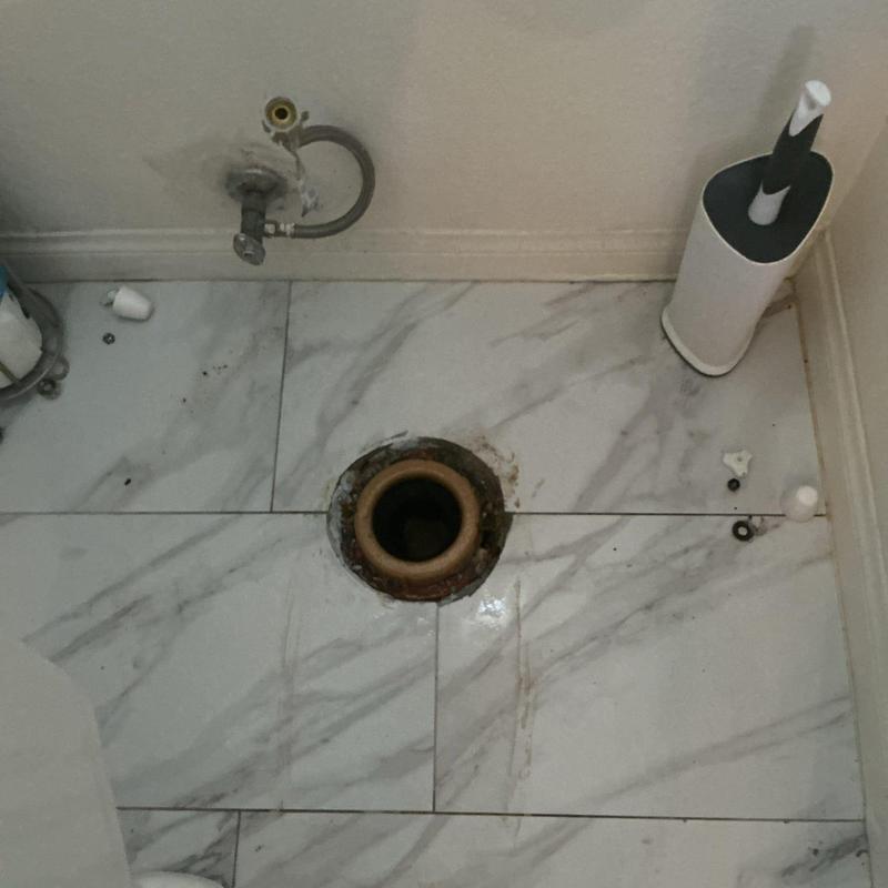 Toilet flange and mounting hardware on tiled floor