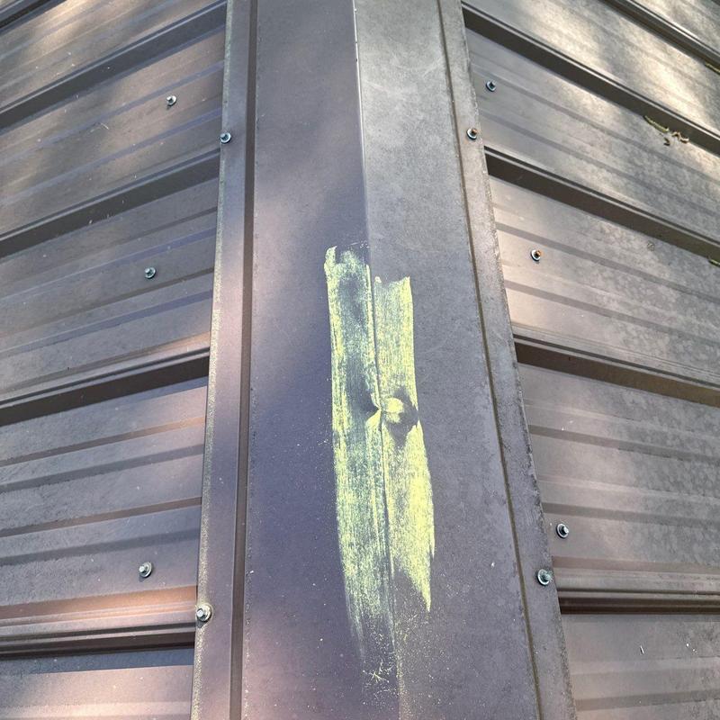 Metal roof panel with hail damage marked in yellow