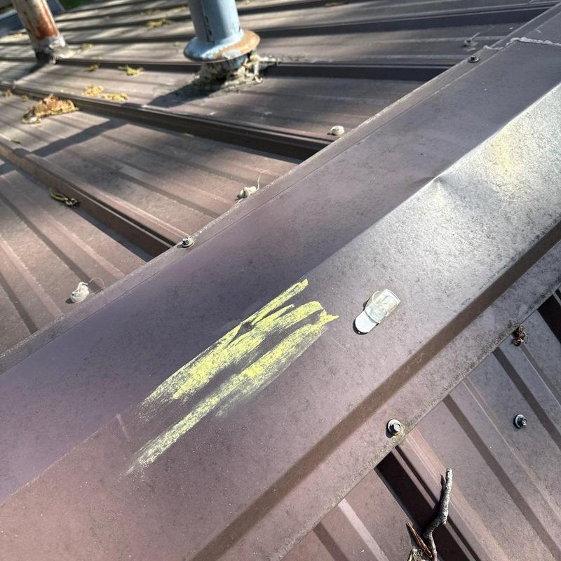 Metal roof panel with chalk marks and sealant around pipe