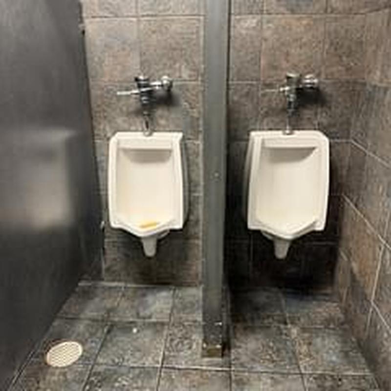 Urinal drains in commercial restroom with tile walls