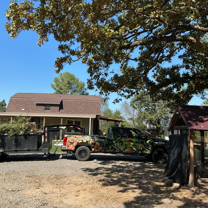 Tree service truck with debris trailer parked by house