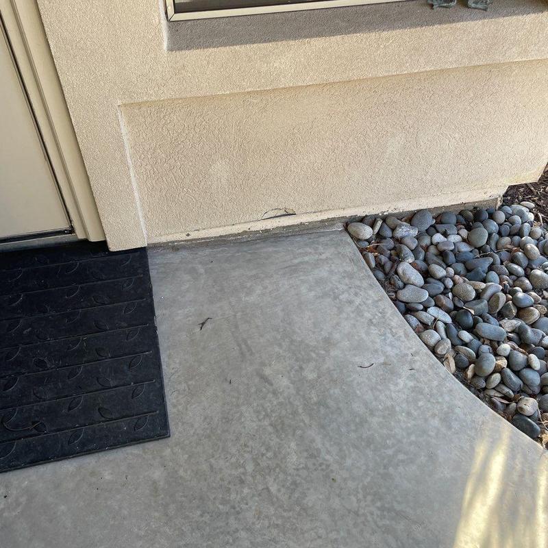 Stucco wall patch near concrete walkway and rocks Stucco wall patch near concrete walkway and rocks