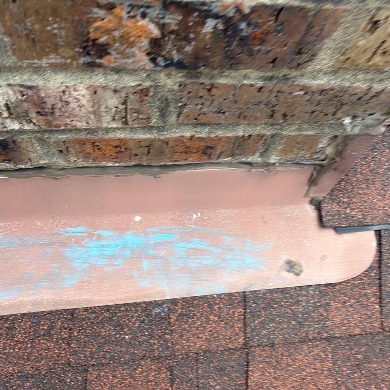 Roof flashing near brick wall with blue marking