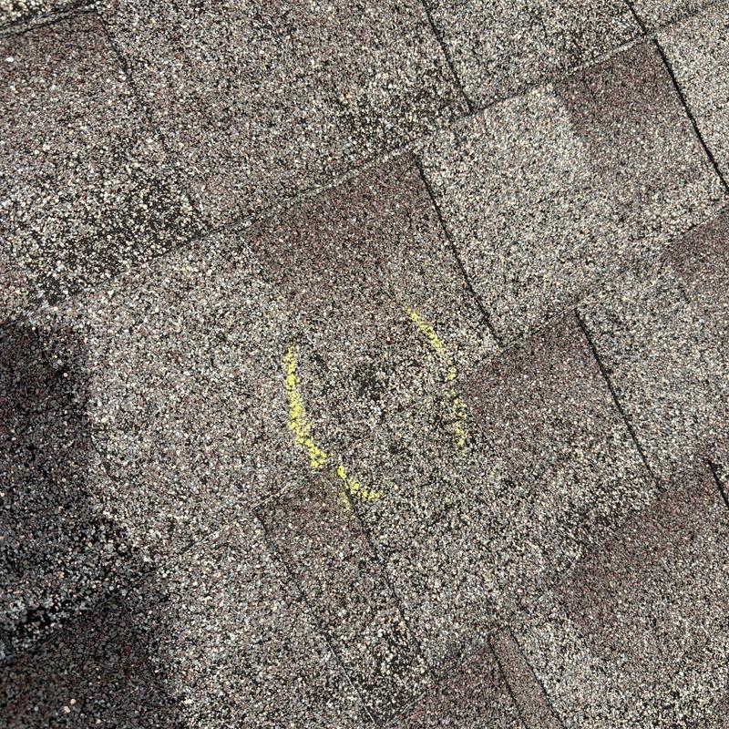 Asphalt roof shingles with marked hail damage spot