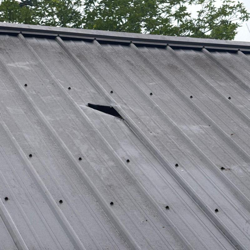 Metal roof panel with visible puncture damage