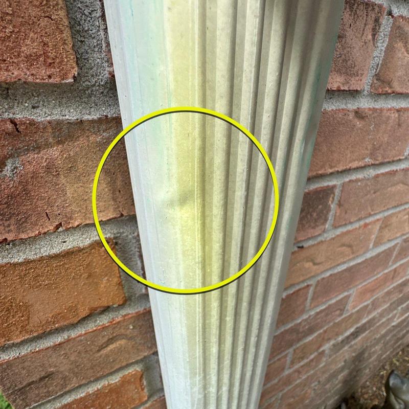 Downspout dent near brick wall on residential building