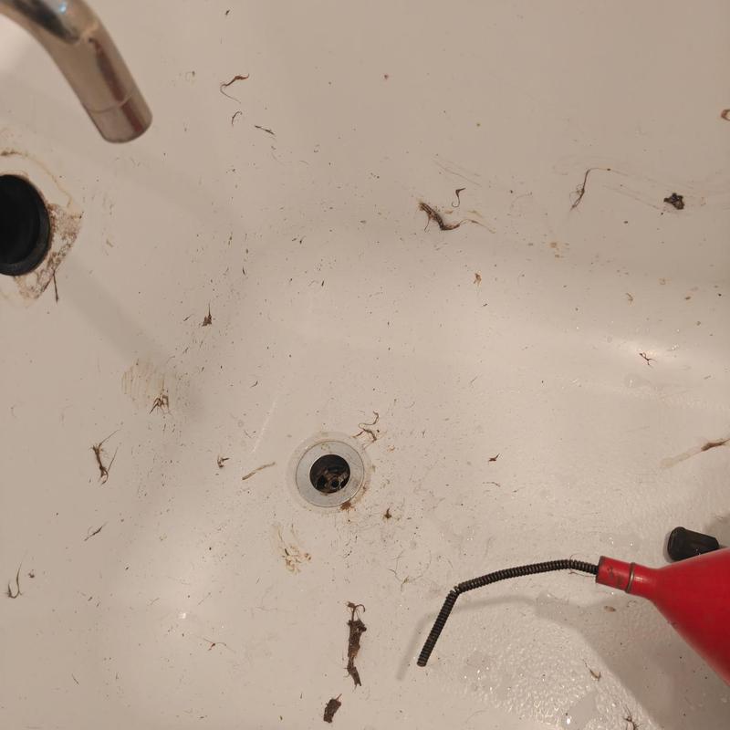 Bathroom sink drain with clogged debris and snake tool