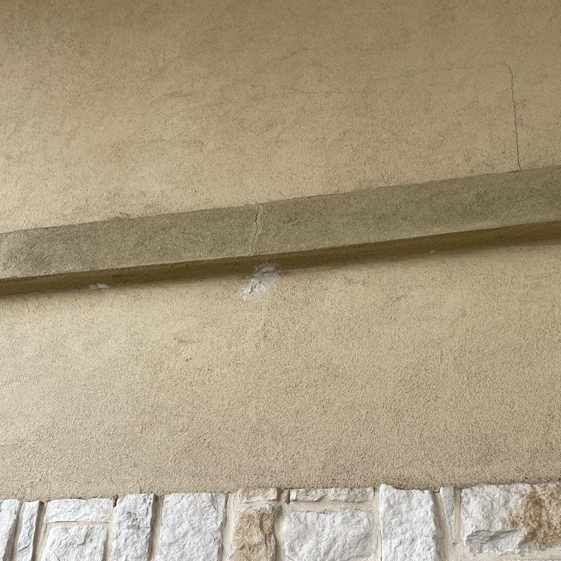 Stucco facade cracks and patches on building exterior Stucco facade cracks and patches on building exterior