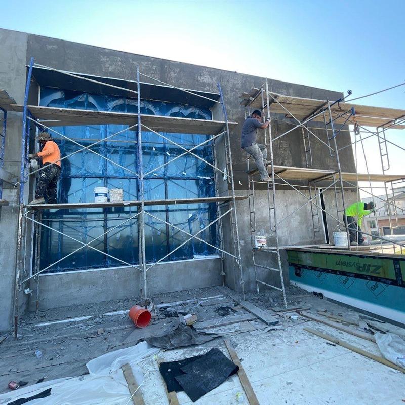 Stucco exterior with scaffolding and workers installing finish Stucco exterior with scaffolding and workers installing finish