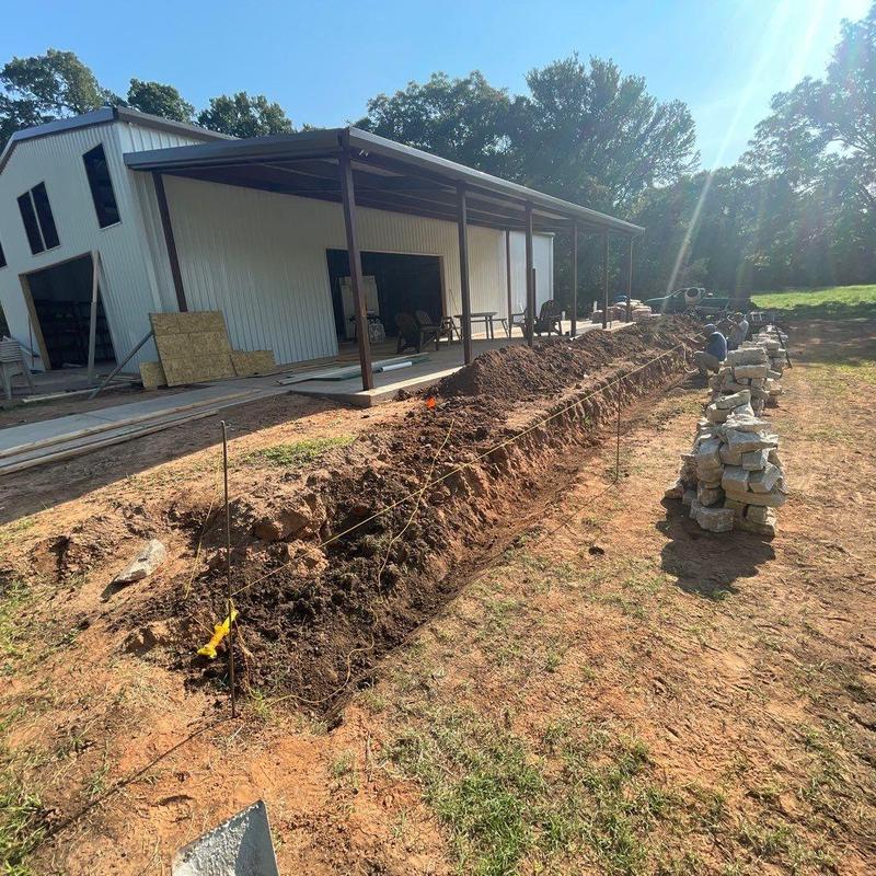 Stone retaining wall foundation trench at outdoor venue Stone retaining wall foundation trench at outdoor venue