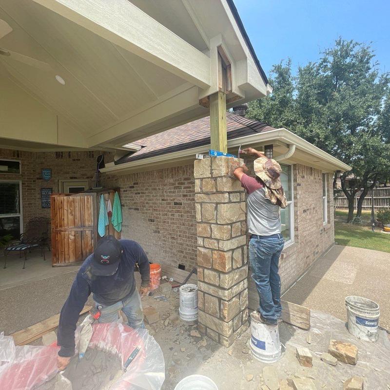 Stone veneer patio column restoration with workers Stone veneer patio column restoration with workers