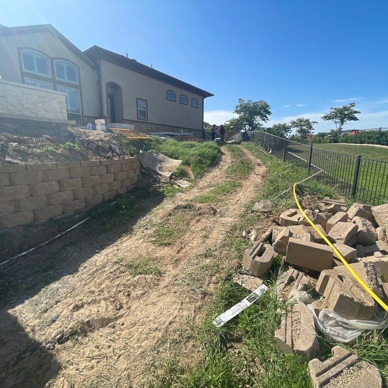 Block retaining wall construction along sloped backyard Block retaining wall construction along sloped backyard