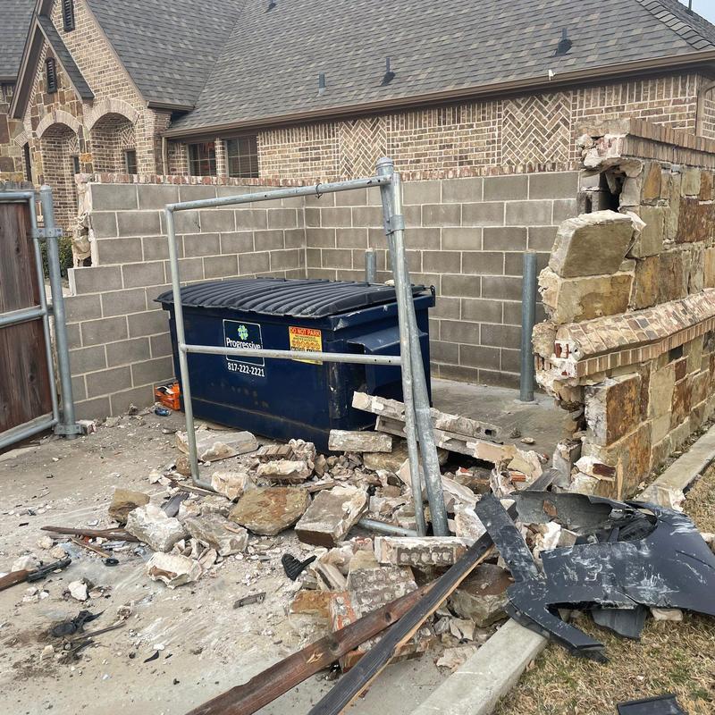Stone and brick wall demolition debris near dumpster Stone and brick wall demolition debris near dumpster