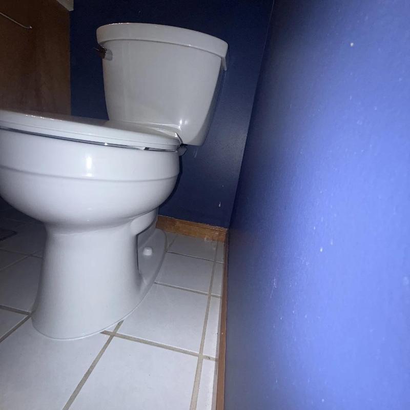 Toilet with leaking floor seal in bathroom corner