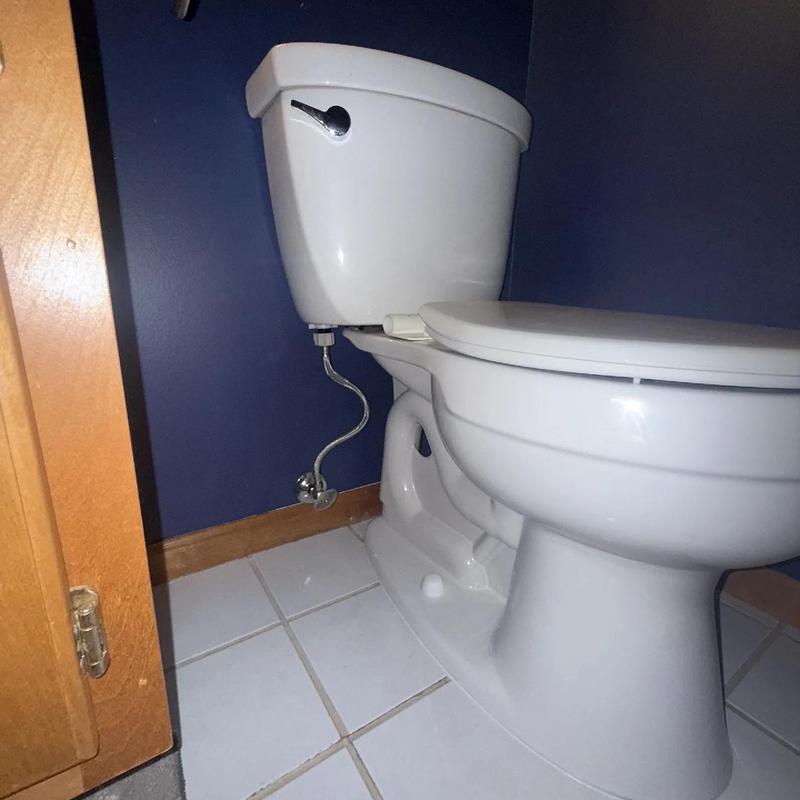 Toilet with water supply line and blue wall background