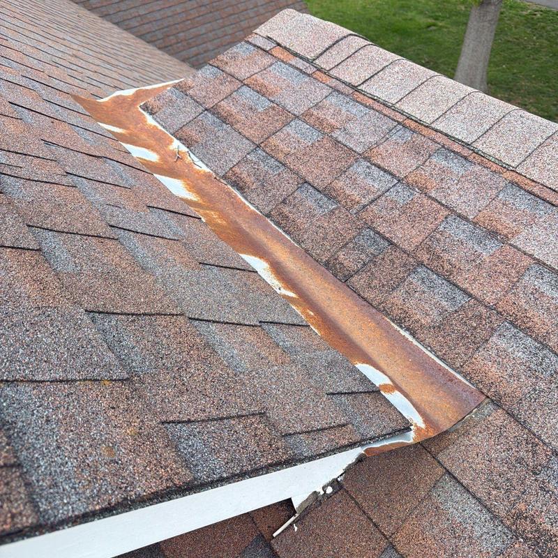 Rusty roof flashing with surrounding asphalt shingles
