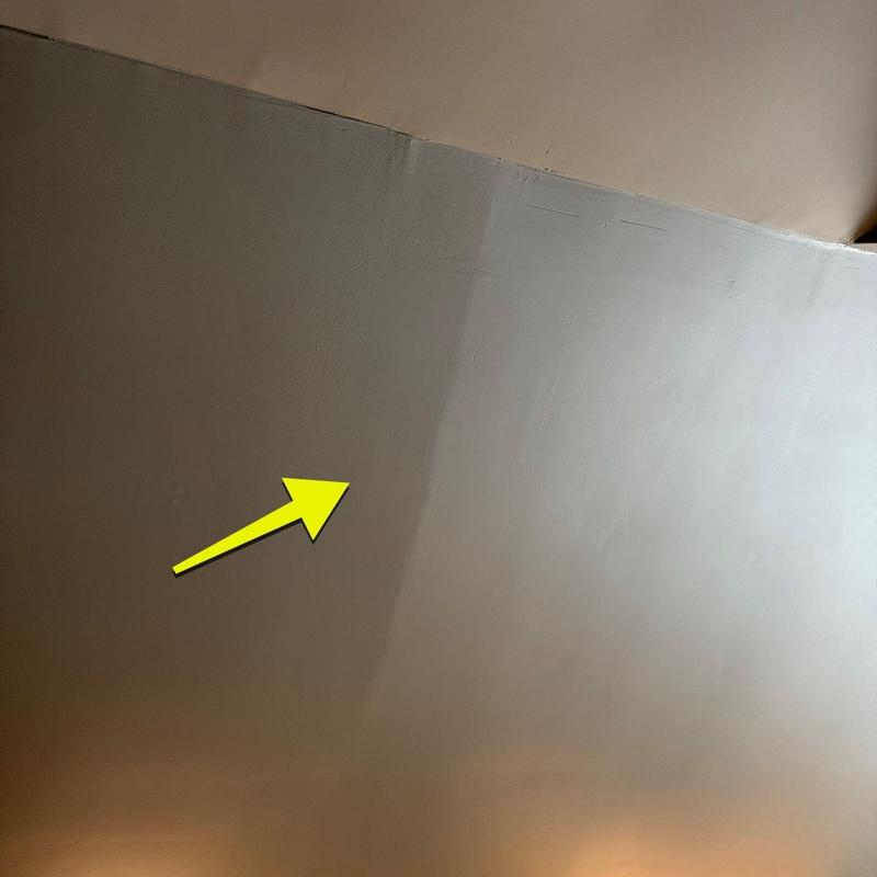 Drywall ceiling with noticeable water stain and arrow