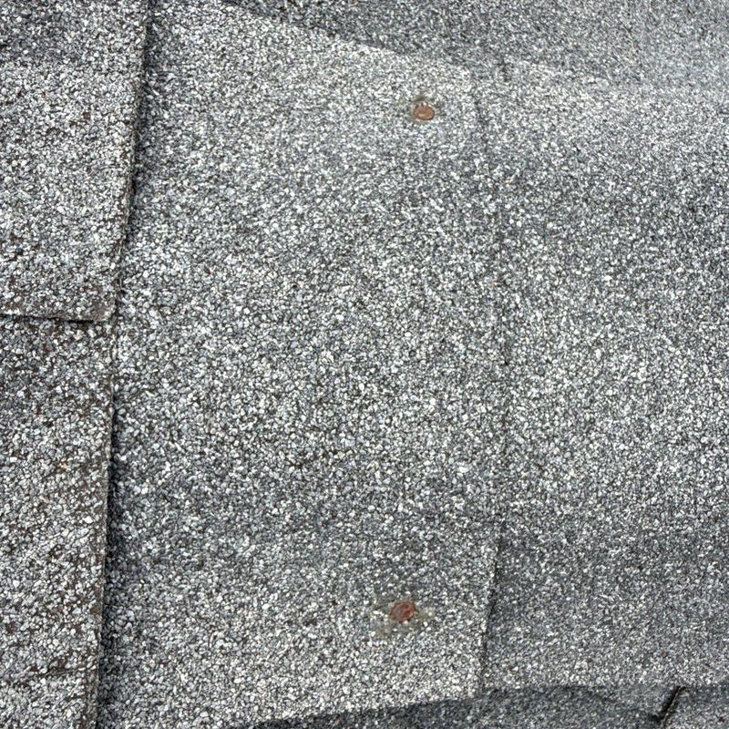 Asphalt shingle roof with nail heads and granule wear