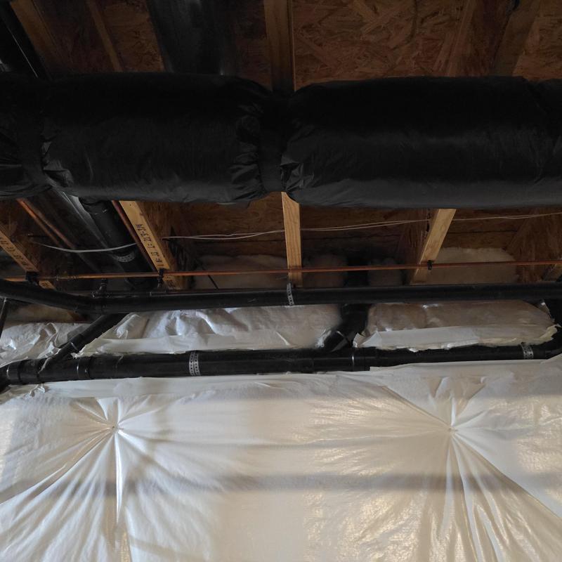 Black PVC drain and vent pipes installed in basement ceiling