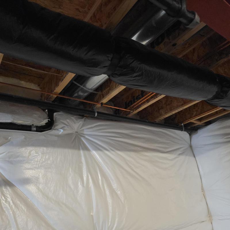 Copper water lines and black PVC piping installation in basement