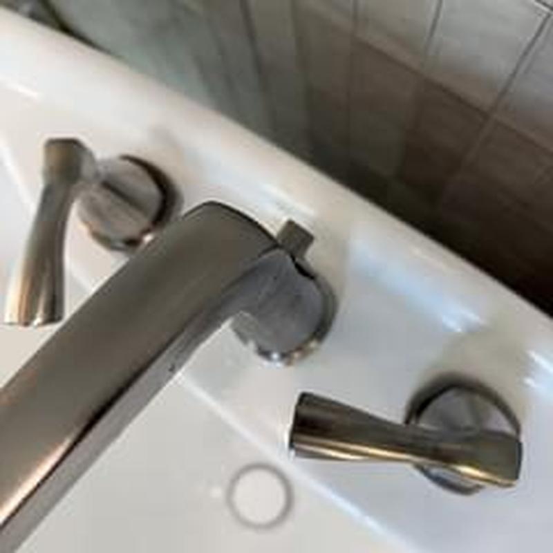 Roman tub faucet with handles on white tub edge
