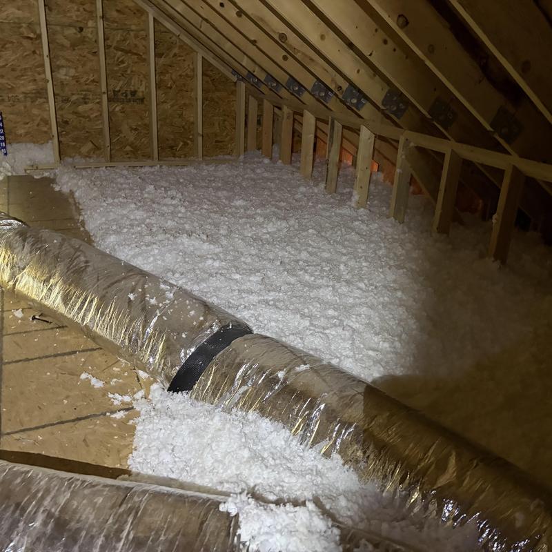 Attic blown-in insulation installation with ductwork in attic