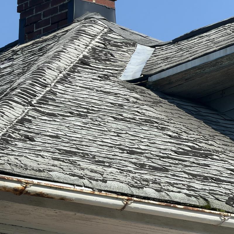 Asphalt shingle roof with severe wind damage and deterioration