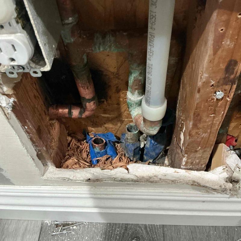 Copper plumbing pipes behind drywall with wood damage
