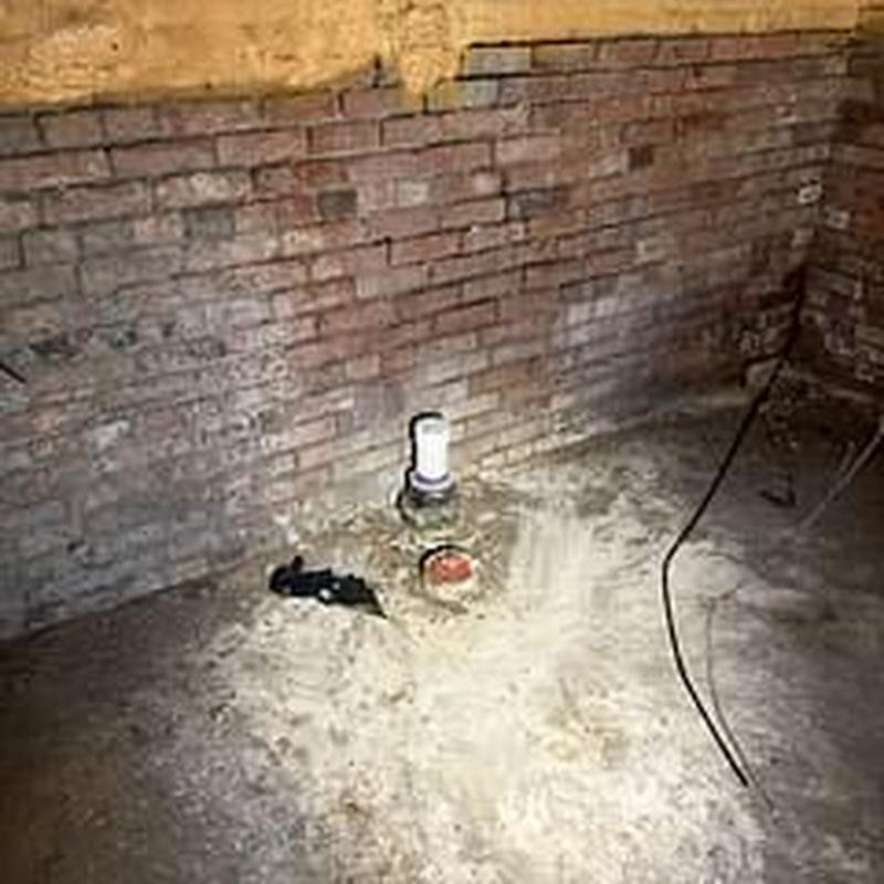 Sewer cleanout pipe in basement near brick wall