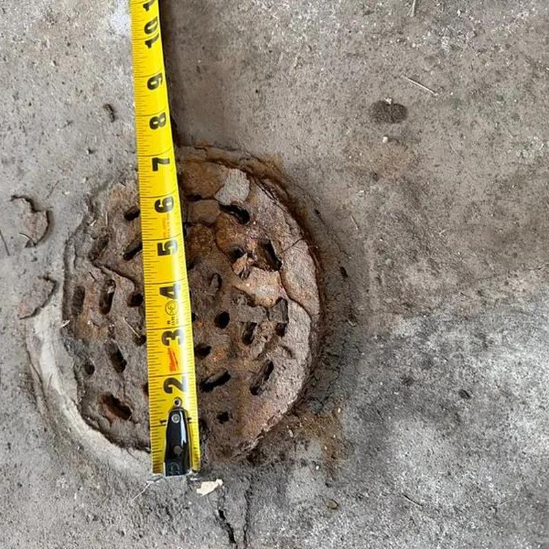 Rusty floor drain cover with measuring tape