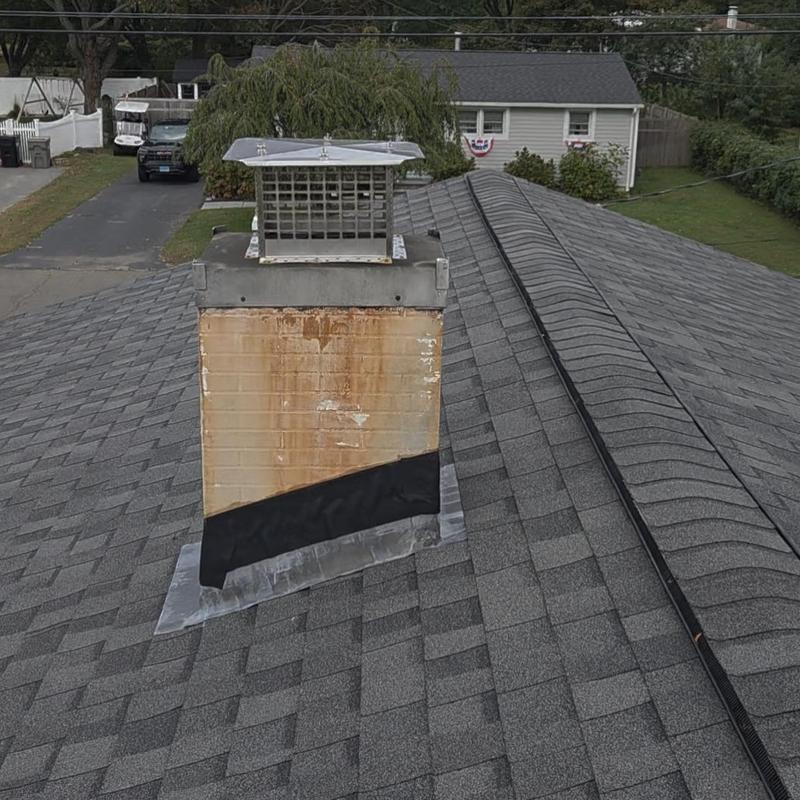 Metal chimney with patched flashing on asphalt shingle roof