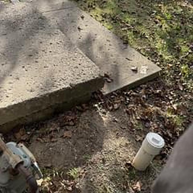 Sewer line cleanout with surrounding concrete slab and soil